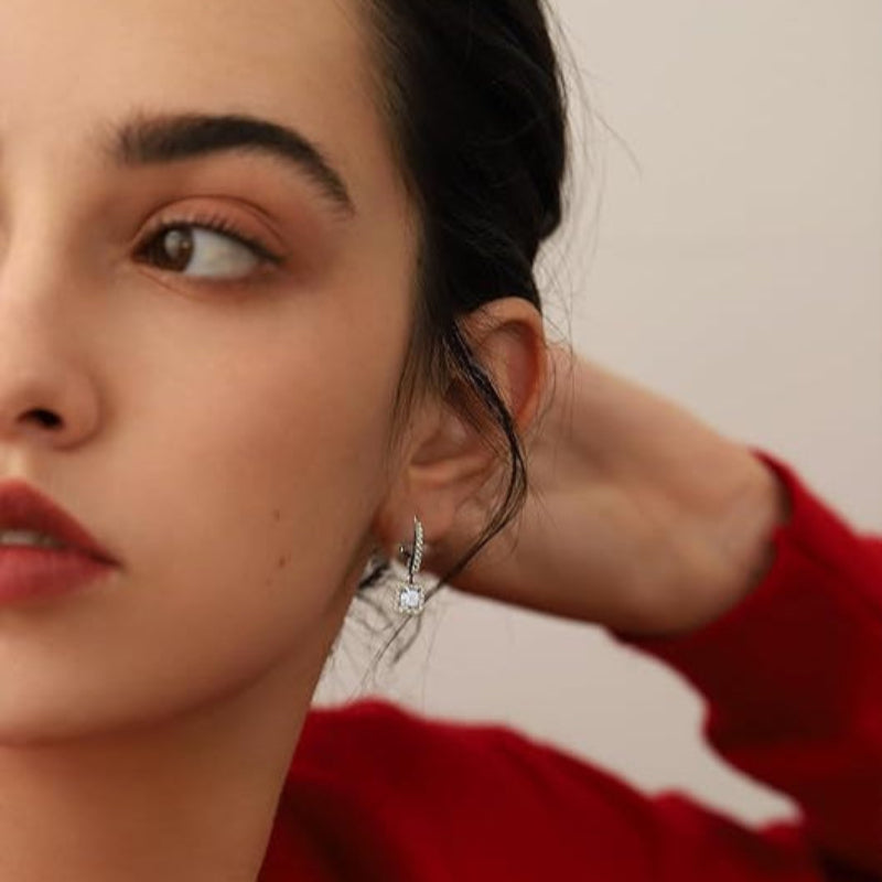 Close-up of a woman wearing a silver earring with a red sweater.